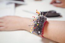 Abgeschnittenes Bild von Nadelkissen am Handgelenk eines Modedesigners im Studio — Stockfoto