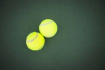 Крупный план двух теннисных мячей на зеленой площадке — стоковое фото