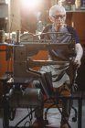 Schuhmacher mit Nähmaschine in Werkstatt — Stockfoto
