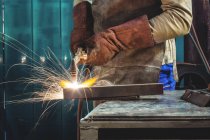 Image recadrée d'un soudeur masculin travaillant sur un morceau de métal en atelier — Photo de stock