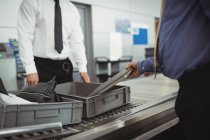 Uomo mettere il computer portatile in vassoio per il controllo di sicurezza in aeroporto — Foto stock