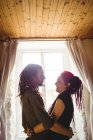 Feliz jovem casal romancia contra janela em casa — Fotografia de Stock