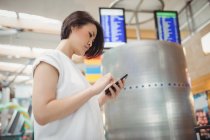 Passagierin benutzt Handy im Flughafen-Terminal — Stockfoto