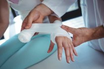 Imagem cortada de terapeuta masculino colocando bandagem na mão paciente feminino na clínica — Fotografia de Stock