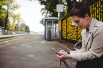 Young woman using mobile phone at railroad station — Stock Photo