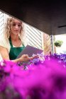 Fiorista femminile che controlla i fiori nel centro del giardino — Foto stock