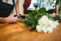 Immagine ritagliata di fiorista femminile ritaglio fiore steli al suo negozio di fiori — Foto stock