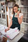 Женщина-флорист проверяет звонки во время разговора по телефону в цветочном магазине — стоковое фото