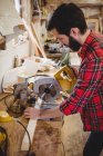Mann sägt Holzbrett mit Motorsäge in Bootswerft — Stockfoto
