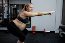 Портрет беременной женщины, выполняющей упражнения на растяжку в спортзале — стоковое фото