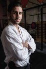 Ritratto di uomo in karategi a braccia incrociate in sala fitness — Foto stock