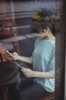 Jeune femme utilisant téléphone portable et tablette numérique dans le café — Photo de stock