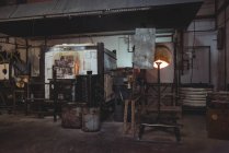 Estación de trabajo vacía y horno en la fábrica de soplado de vidrio - foto de stock