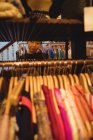 Молодая женщина выбирает одежду на вешалках в магазине одежды — стоковое фото