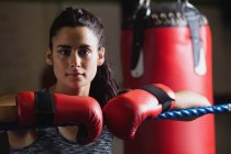 Porträt eines attraktiven Boxers in Handschuhen, der sich im Fitnessstudio an das Seil des Boxrings lehnt — Stockfoto