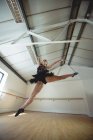 Vue à faible angle de Ballerina pratiquant la danse de ballet et sautant en studio — Photo de stock