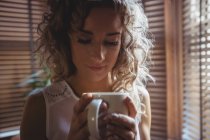 Primo piano di bella donna che prende un caffè in soggiorno a casa — Foto stock