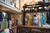 Femme sélectionnant un vêtement dans les cintres au magasin de la boutique — Photo de stock
