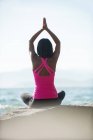 Vista trasera de la mujer realizando yoga sobre roca en día soleado - foto de stock