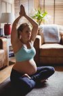 Bela mulher grávida realizando ioga na sala de estar em casa — Fotografia de Stock