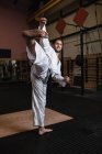 Uomo sorridente che pratica karate in palestra — Foto stock