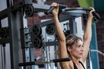 Жінка, виконуючи розтягування вправи з витягнутим бар в спортзалі — стокове фото