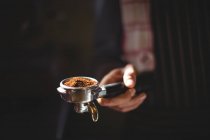 Mid section of waiter holding portafilter filled with ground coffee in cafe — Stock Photo