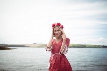 Беззаботная блондинка в цветочной тиаре и стоящая у реки — стоковое фото