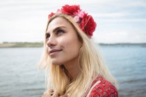 Портрет беззаботной блондинки в цветочной тиаре, смотрящей вверх возле реки — стоковое фото