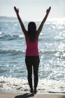 Vista posteriore della donna che pratica yoga sulla spiaggia nella giornata di sole — Foto stock
