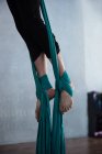 Gros plan de gymnaste faisant de l'exercice sur corde en tissu bleu dans un studio de fitness — Photo de stock