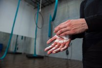 Gymnast rubbing chalk powder on hands in fitness studio — Stock Photo