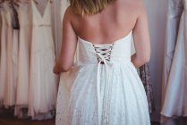Schöne Frau probiert Hochzeitskleid in einem Geschäft im Atelier an — Stockfoto