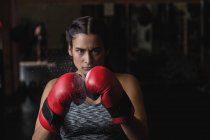 Portrait of woman in boxing gloves looking at camera at fitness studio — Stock Photo