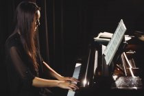 Schöne Frau, die im Musikstudio ein Klavier spielt — Stockfoto