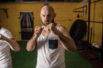 Портрет двух боксеров, стоящих в спортзале и смотрящих в камеру — стоковое фото