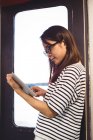 Junge Frau lehnt sich mit digitalem Tablet an Wand — Stockfoto