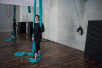 Female gymnast holding fabric rope in fitness studio — Stock Photo