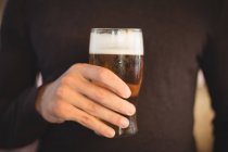 Partie médiane de l'homme tenant un verre de bière au bar — Photo de stock