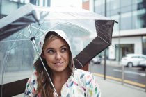 Hermosa mujer sosteniendo paraguas durante la temporada de lluvias - foto de stock