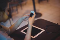 Жіночі текстові повідомлення на мобільному телефоні в кафе — стокове фото