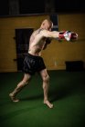Shirtless tattooed thai boxer practicing in gym — Stock Photo
