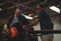 Équipe de souffleurs de verre façonnant le verre fondu à l'usine de soufflage de verre — Photo de stock