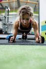 Mujer realizando ejercicio push-up en el gimnasio - foto de stock
