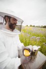 Apicultor usando fumante de abelha em campo — Fotografia de Stock