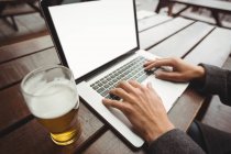 Gros plan de l'homme utilisant un ordinateur portable dans le bar — Photo de stock