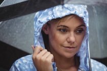 Mulher atenciosa segurando guarda-chuva durante a estação chuvosa — Fotografia de Stock