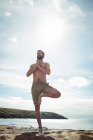 Uomo che esegue yoga sulla spiaggia — Foto stock
