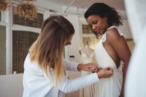 Женщина примеряет свадебное платье в студии при содействии модельера — стоковое фото