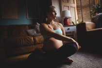 Femme enceinte s'étirant dans le salon à la maison — Photo de stock